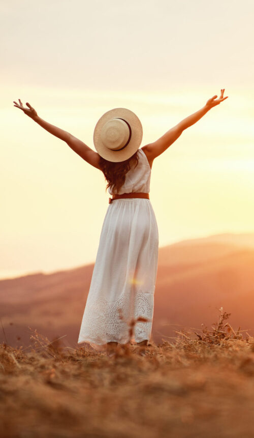 Happy woman standing with her back on sunset in nature